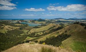 a view of a valley of hills with a lake at Hiwi at Tahi - luxury bungalow with seaviews in Pataua