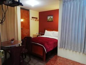 Habitación de hotel con cama y mesa en Hostal Sumak'usi, en Juliaca