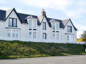 ein großes weißes Haus mit einem weißen Zaun in der Unterkunft Tammie Norrie Cottage in Banff