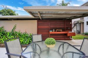 a patio with a glass table and chairs and a desk at Nautilus Beachside Apartments in Bargara