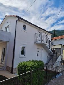 uma casa branca com varanda e escadas em Apartmani Vanja em Baošići