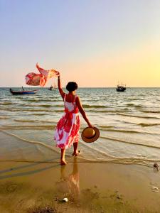 a woman standing on the beach flying a kite at Villa Cha Cha Chaolao Beach Resort in Chao Lao Beach