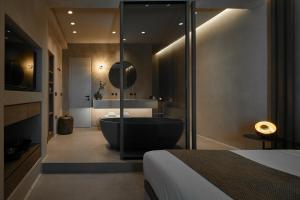 皮尔戈斯Halcyon Days Suites的一间带黑色浴缸的浴室和一间卧室