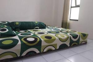 a bed in a room with a green and white comforter at Anindya House in Magelang