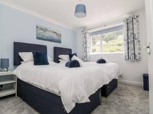 two beds in a bedroom with a large window at Beach Cottage in Redruth