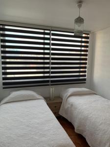 um quarto com 2 camas e uma grande janela em Departamento Amoblado Talca em Antofagasta