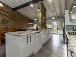 a kitchen with white cabinets and a brick wall at Bay Parklands 4, 2 Gowrie Avenue - pool & tennis court in Nelson Bay