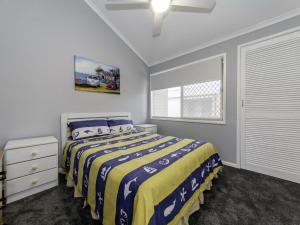 a bedroom with a bed with a yellow and blue blanket at Bay Parklands 4, 2 Gowrie Avenue - pool & tennis court in Nelson Bay +18 photos