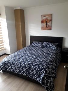 a bedroom with a bed with a blue and white comforter at Moderno departamento 3B en Condominio La Victoria in Cuenca