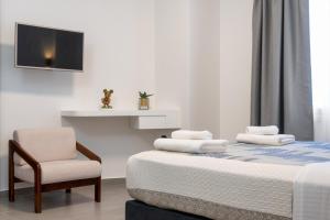 um quarto com uma cama com uma cadeira e uma televisão em Glyfada Gallery Apartment em Atenas