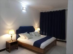 a bedroom with a bed and two lamps and a window at Villa Bunyonyi in Kabale