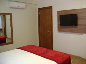 a bedroom with a bed and a flat screen tv at Hotel Areias Brancas in Rosário do Sul