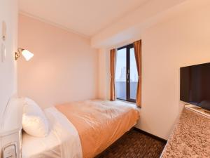 a hotel room with a bed and a flat screen tv at Kobe Sannomiya Union Hotel in Kobe