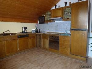 eine Küche mit Holzschränken und einem Kühlschrank aus Edelstahl in der Unterkunft Ferienwohnung Fernblick in Freyung