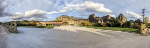 a building on a road with a mountain in the background at Grand Meteora Hotel in Kalabaka