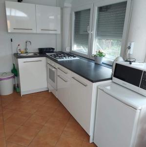 a kitchen with white cabinets and a black counter top at Rege apartman 2 in Alsóörs