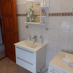 a white bathroom with a sink and a mirror at Rege apartman 2 in Alsóörs
