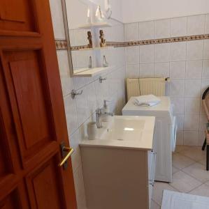 a white bathroom with a sink and a mirror at Rege apartman 2 in Alsóörs