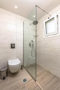 a bathroom with a toilet and a glass shower at Breeze Luxury Rooms in Laganas