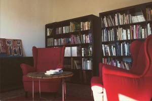 a library with two chairs and a table and books at La casa di Montegiardino in San Marino