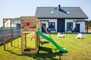 un parque infantil con un aro de baloncesto y un tobogán en Domki całoroczne Lighthouse, en Władysławowo