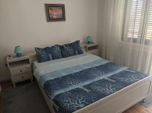 een slaapkamer met een bed met een blauw dekbed en kussens bij Sokobanja Apartmani in Soko Banja