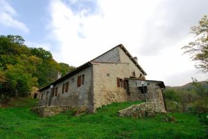 een oud stenen gebouw op een grasheuvel bij A stay surrounded by greenery - Agriturismo La Piaggia - in Vivo dʼOrcia