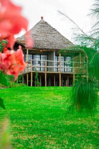 a large house with a thatched roof on a green lawn at Kutoka Lodge in Arusha