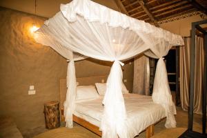 1 dormitorio con cama con dosel y cortinas blancas en Kutoka Lodge en Arusha