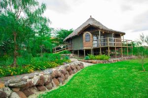 a house with a stone retaining wall in front of a yard at Kutoka Lodge in Arusha