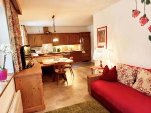 ein Wohnzimmer mit einem roten Sofa und einer Küche in der Unterkunft Ferienwohnung Resi im Zentrum in Fusch an der Glocknerstraße
