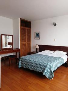 a bedroom with a bed and a desk and a mirror at Room in Guest room - Comfotable Room in excelent location in Bogotá