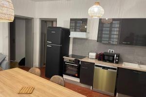 a kitchen with a table and a black refrigerator and a stove at République :Appartement T3 Centre historique in Perpignan