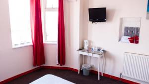 a room with red curtains and a tv and a bed at Hello Roomz - Pleasure Beach in Blackpool