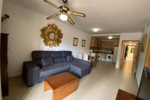 a living room with a blue couch and a ceiling fan at Apartamento Playa Marina Particular Isla Canela in Huelva