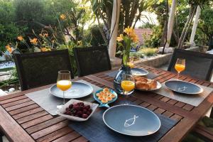 una mesa de madera con platos de comida y vasos de zumo de naranja en SECRET PARADISE-Holiday home with hot tub and BBQ, en Lopud Island