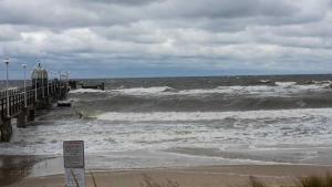 a beach with a pier and waves in the ocean at FeWo Gretel in Zinnowitz