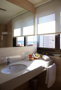 a bathroom with a sink and a large mirror at Hotel Coia de Vigo in Vigo