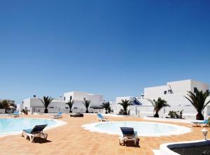a swimming pool with two lounge chairs in front of a building at Alojamiento Vacacional con balcón La Vela in Puerto Calero