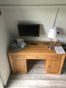 a wooden desk with a television and a lamp on it at Gracelands Glamping in Ballyronan