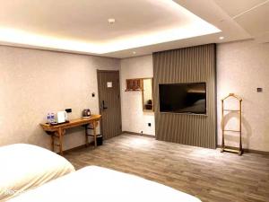 een slaapkamer met een bed, een bureau en een televisie bij Xi'an Huiya Tianmu Hotel in Xi'an