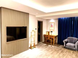 a living room with a television and a chair and a table at Xi'an Huiya Tianmu Hotel in Xi'an