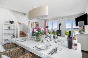 a dining room with a white table with flowers on it at Bellevue in Olpenitz