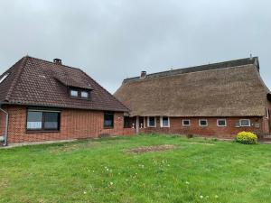 ein großes Backsteinhaus mit einem Strohdach in der Unterkunft Helene in Loxstedt