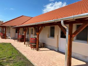 a patio with tables and chairs under a roof at Tisza-i Apartmanok in Tiszafüred