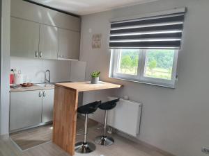 a kitchen with two bar stools and a window at Apartmani Fenestra in Otočac