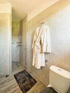 a bathroom with a shower and a white robe on a wall at Apartmani Fenestra in Otočac