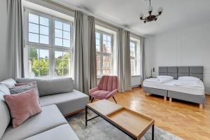 a living room with a couch and a bed and windows at Goma Rent - Szeroka Old Town in Gdańsk