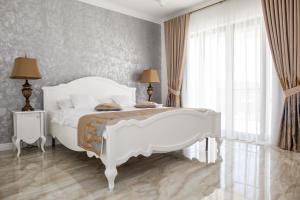 a bedroom with a white bed and a large window at Pensiunea Carpe Diem Spa in Dumbrăviţa