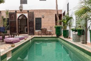 una piscina en medio de una casa con palmeras en Riad Ayada, en Marrakech
